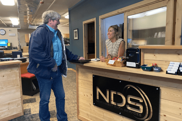 Image of a person talking with another person behind a desk at Northwest Data Services.