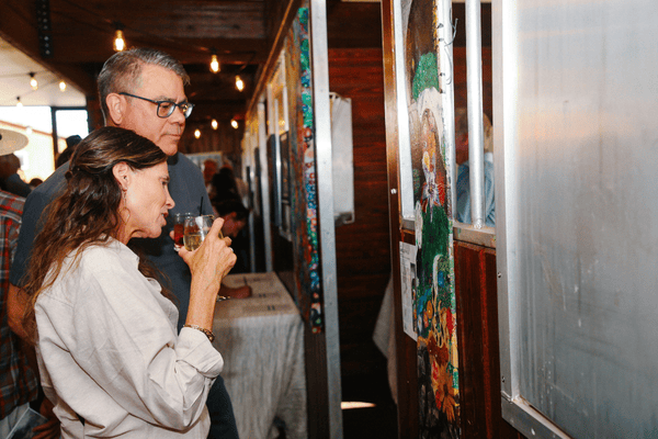 Photo of two people standing and looking at a piece of art on a wall.