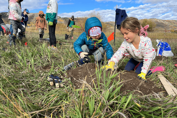 Image of two girls planting a tree sapling together.