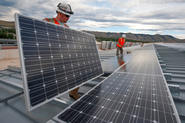 Photo of two workers installing solar panels.