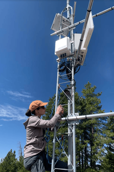 Photo of a person working on a climate monitoring station harnessed in.