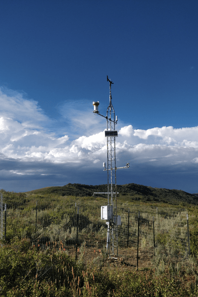 Image of a YBASIN station, a tall set of poles and measuring devices, in a field.
