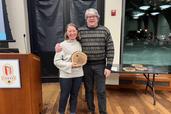 Image of two people standing together with an award and smiling.